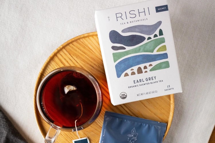 A box of Rishi Tea and Botanicals Earl Grey tea next to a glass mug of tea
