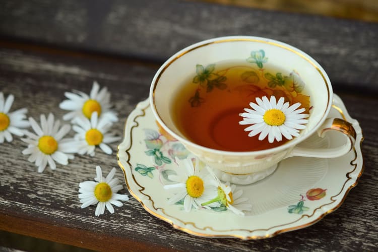 A cup of tea with flower petals sprinkled around it