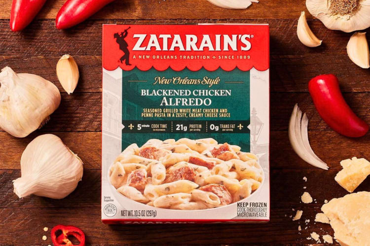 A box of Zatarain’s Blackened Chicken Alfredo surrounded by garlic cloves and chiles