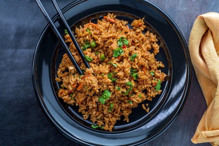 Aerial view of a bowl of chicken-fried rice with chopsticks