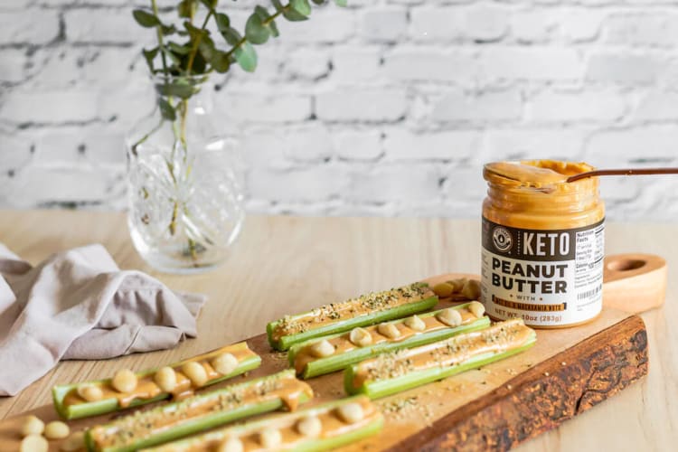 A bottle of one of the best keto peanut butters from Left Coast Performance, next to peanut butter snacks