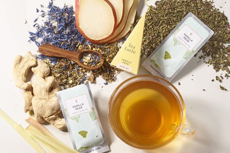 Ginger, tea leaves, a glass mug of tea and pear slices with Tea Forté sachets