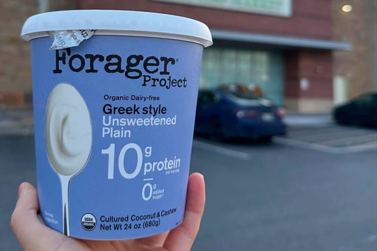 A hand holding a tub of Forager Project Unsweetened Yogurt 