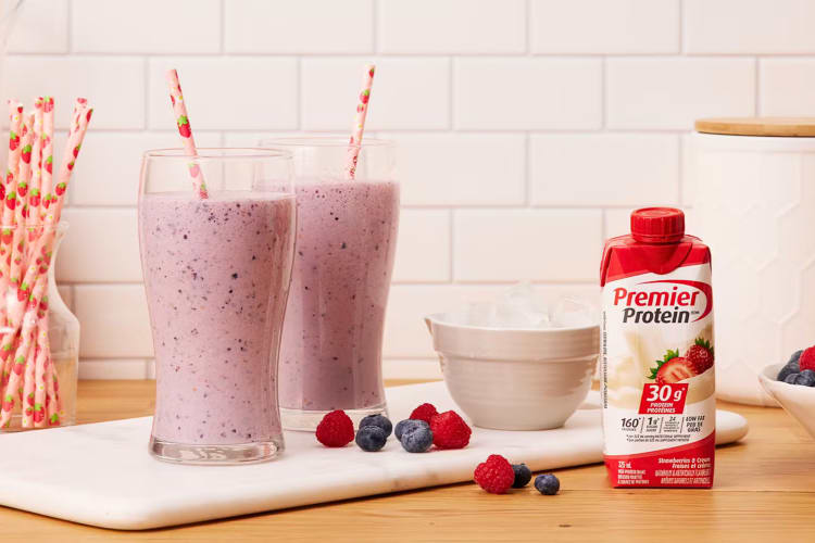 A carton of Strawberries and Cream Premier Protein next to two smoothies