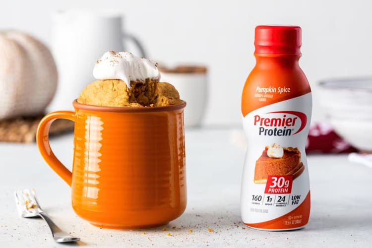 A bottle of Pumpkin Spice Premier Protein next to a pumpkin spice latte