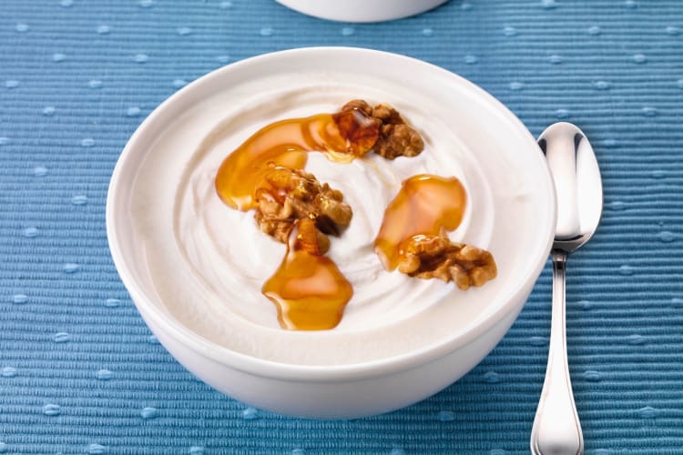 A bowl of Greek yogurt with honey and walnuts.
