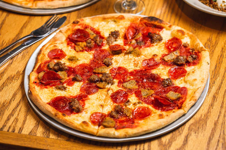 The Supreme pizza on a metal tray, next to a knife and fork, from BarDough