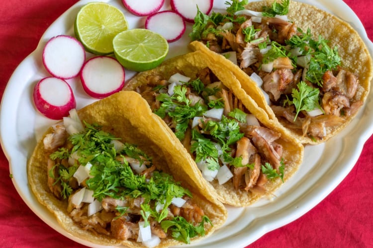 Carnitas tacos served with cilantro and onions