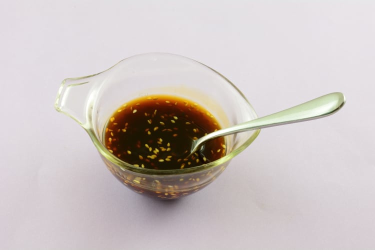 A glass jar of teriyaki sauce with sesame seeds 