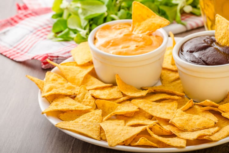 Tortilla chips on a plate next to two types of dip