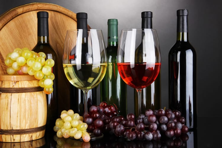 Two glasses of wine, five bottles, bunches of grapes and two barrels