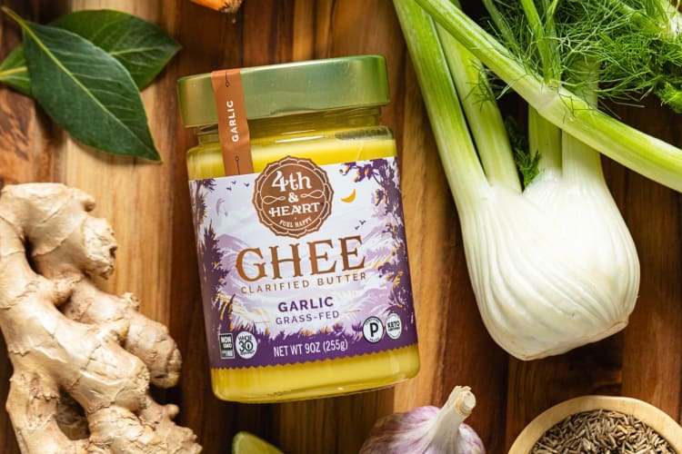 A tub of 4th and Heart Ghee, one of the best Whole Foods products, surrounded by vegetables