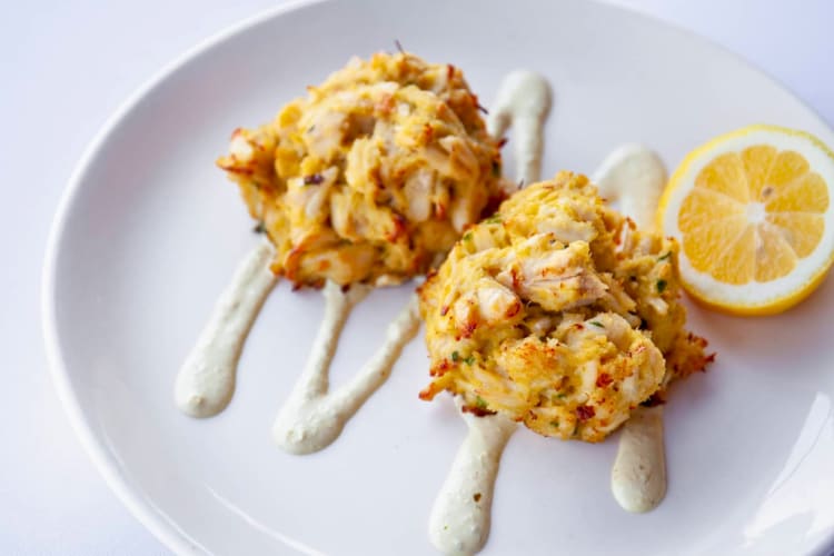 Savory crab cakes served sauce and a lemon