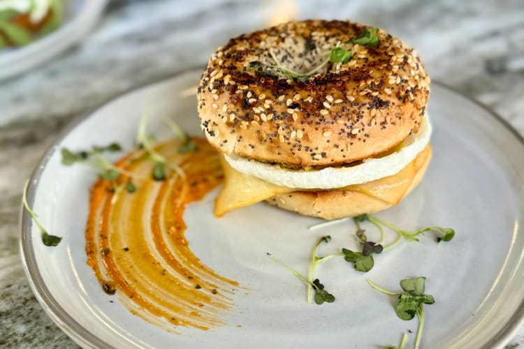 everything bagel sandwich filled with sausage, cheddar cheese and an egg patty