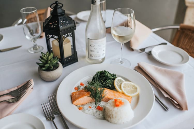 a table laid with wine, a plate of salmon and place settings