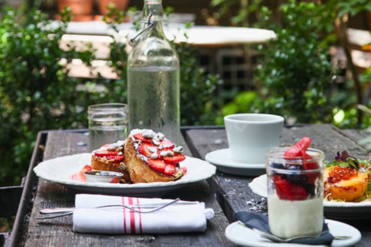 An outdoor table full of breakfast food.
