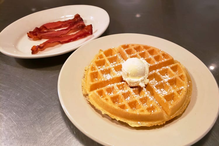 Belgian waffles topped with butter and a side of bacon