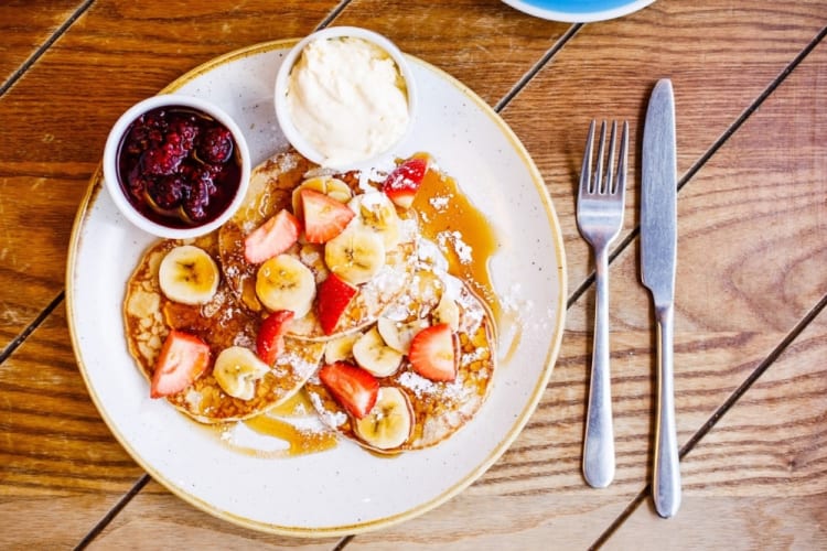 Pancakes, banana and strawberry on a white plate