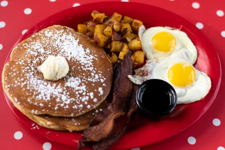Two pancakes topped with powdered sugar & whipped butter. Served with two eggs any style, home fries & your choice of breakfast meat.