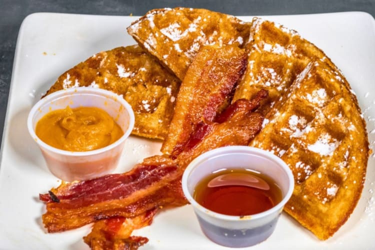 Sweet potato waffles served with powered sugar, bacon and maple syrup