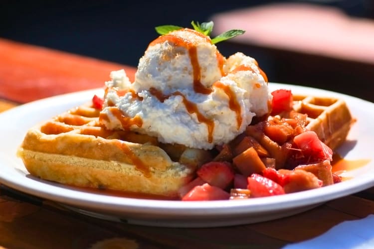 Waffles topped with whipped cream, strawberries and drizzled with caramel sauce