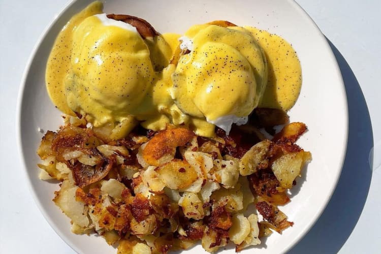 eggs Bendecit topped with hollandaise sauce and served with home fries.