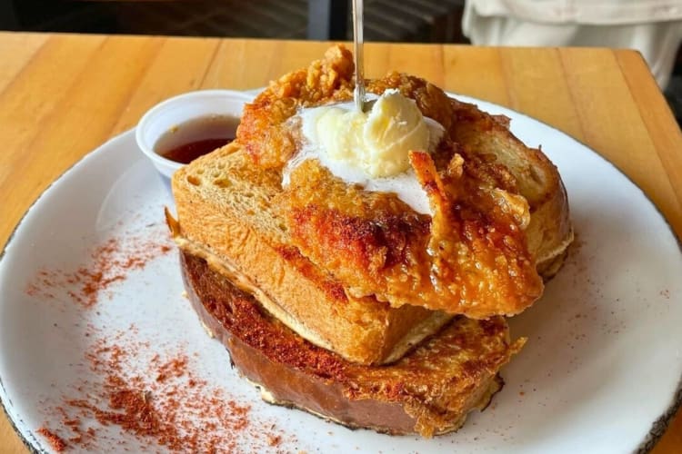 two cinnamon dipped challah french toast served with crispy fried chicken, whipped butter and syrup