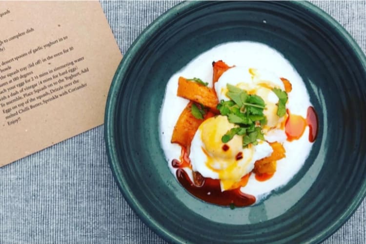 A bowl of poached eggs paired with squash and a white sauce