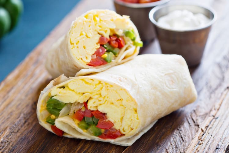 Breakfast burrito served with scrambled eggs and vegetables