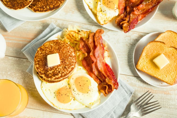 Breakfast dishes, including pancakes, bacon and eggs on a table