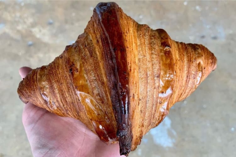 A freshly baked croissant in someone's hand