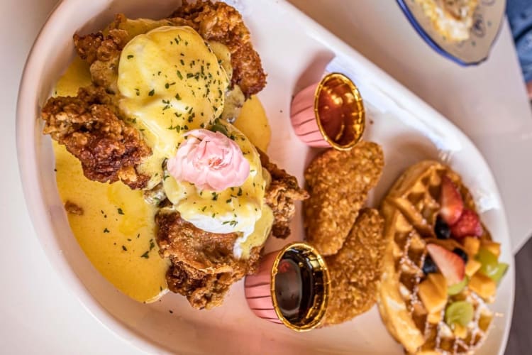 Chicken waffle Benedict served with hash browns and fruit crowned waffle