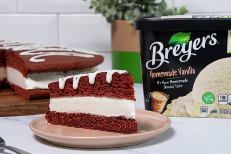 A tub of Breyers ice cream next to a slice of red cake and the rest of the cake