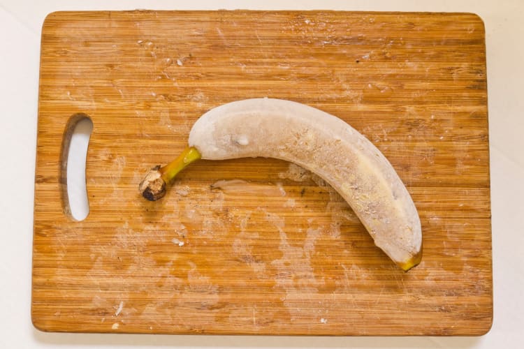 Frozen whole banana on a wooden table