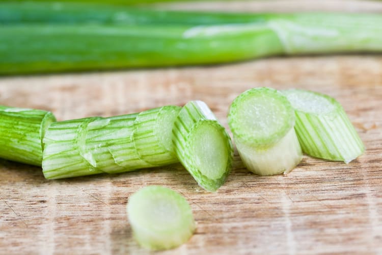 Chopped green onions on a wooden board.