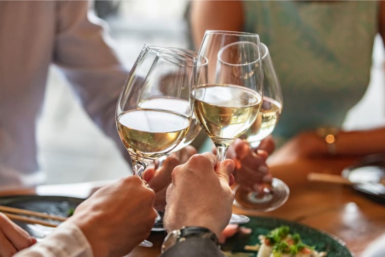 Four people raise glasses of white wine together