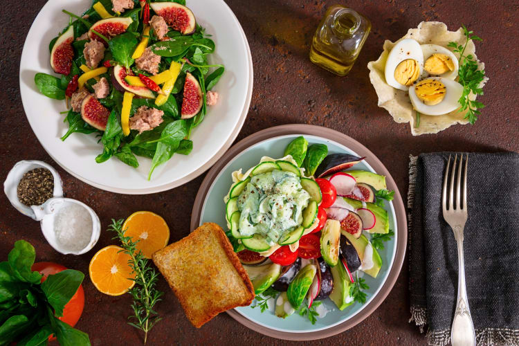 Two different salads and a bowl of boiled eggs on a table