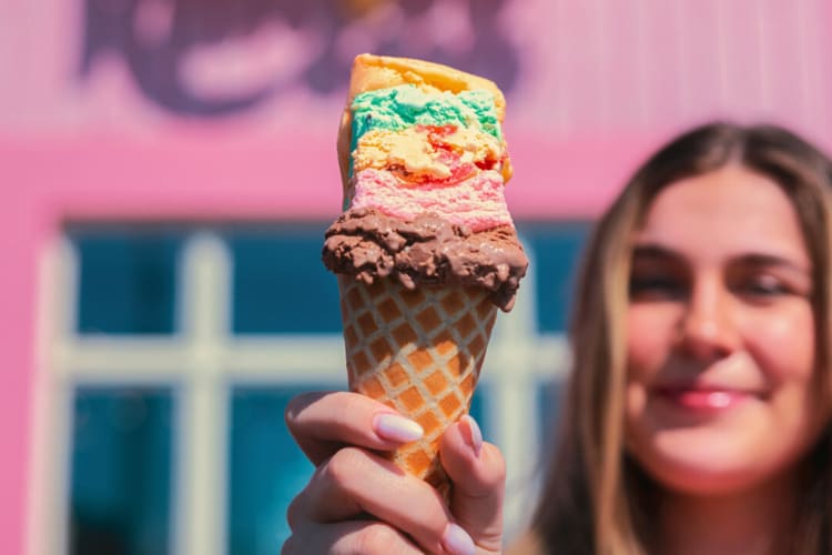 A woman holding a Rainbow Cone from The Original Rainbow Cone, a sugary Chicago food