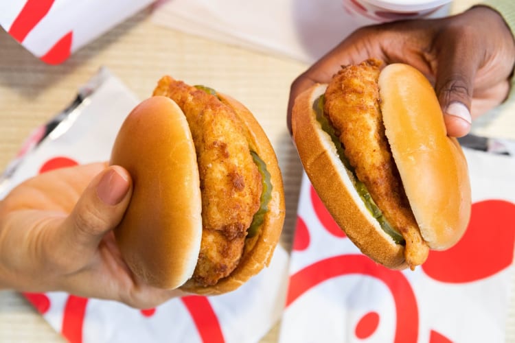 Two hands holding two Chick-fil-A chicken sandwiches