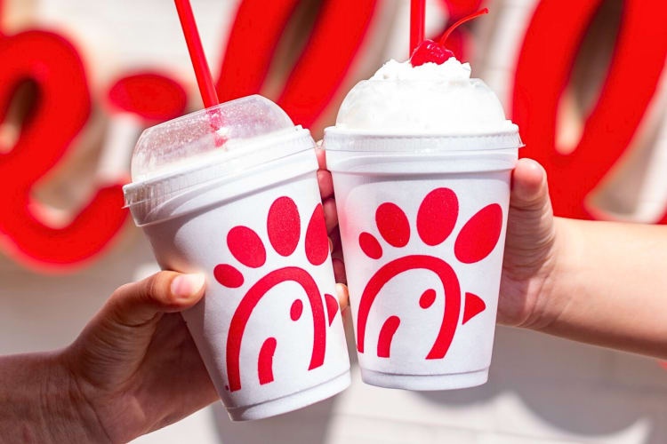 Two hands holding two Chick-fil-A drinks in takeaway cups
