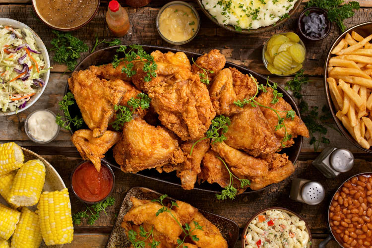 A plate of fried chicken pieces surrounded by various sides
