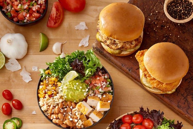 A variety of chicken fast foods, including a fried chicken sandwich, a grilled chicken sandwich and a chicken salad bowl.