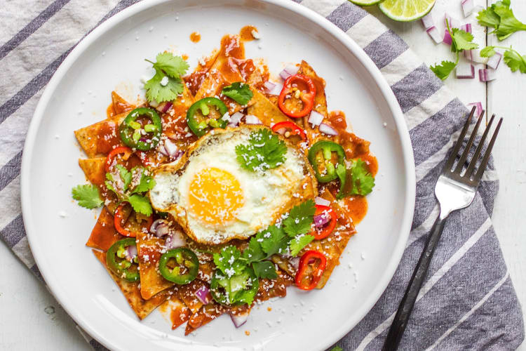 Aerial view of chilaquiles on a plate with an egg and sliced jalapeños 