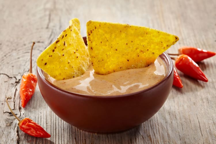 Nachos dipped into spicy queso sauce.