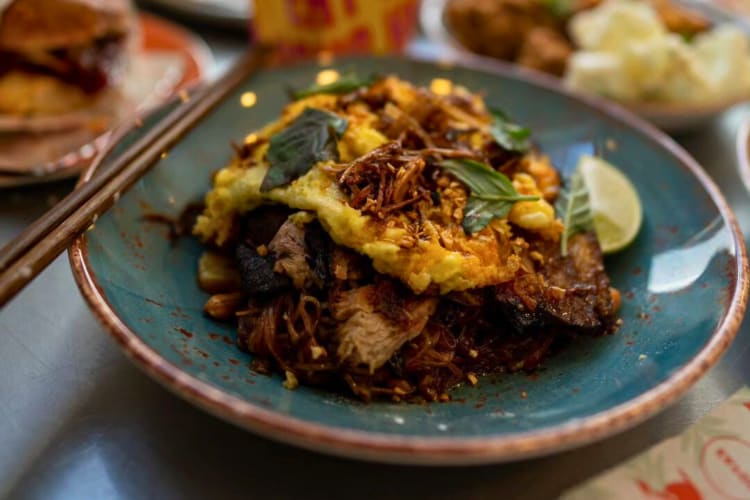 Pad thai served with noodles pork, a fried omelet and vegetables