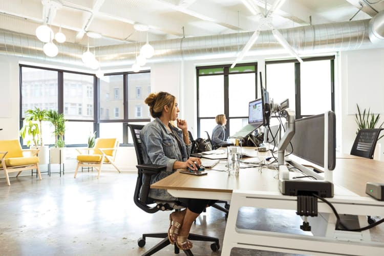 Two women working on laptops in a communal workspace at Platform Coworking