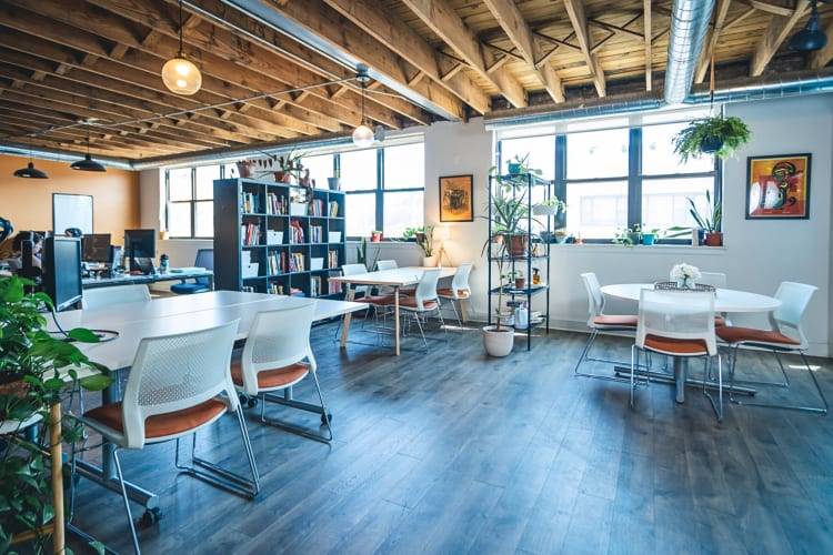 A workspace with tables, chairs, computers and bookshelves, at Second Shift