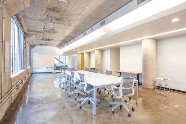A boardroom area with a table and chairs, at One Three, a coworking space in Chicago