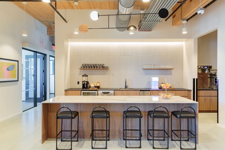 A kitchen at Industrious with a counter, chairs and kitchen essentials
