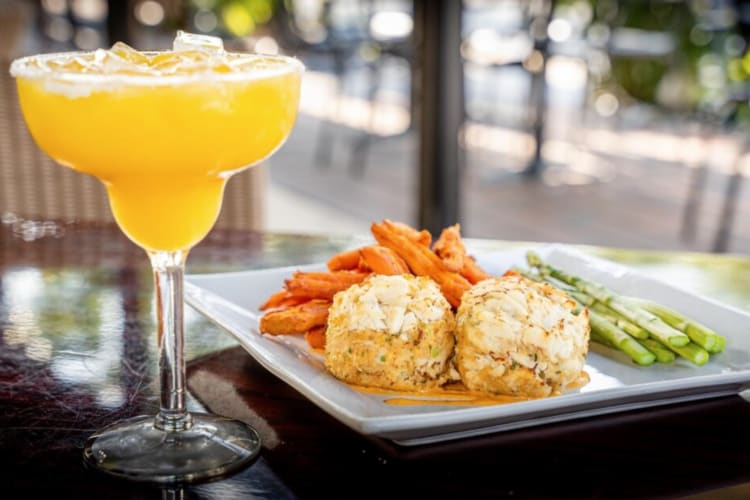 crab cakes on a plate beside a cocktail